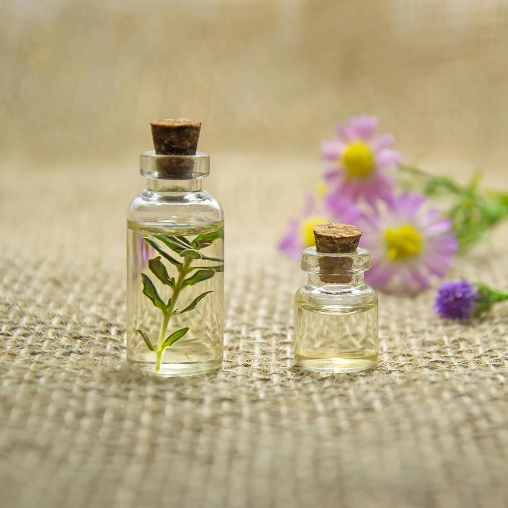 Kleine Glasflaschen mit pflanzlichen Ölen und Blüten
