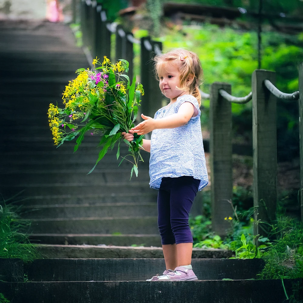 Kleines Mädchen hält einen Blumenstrauß im Grünen