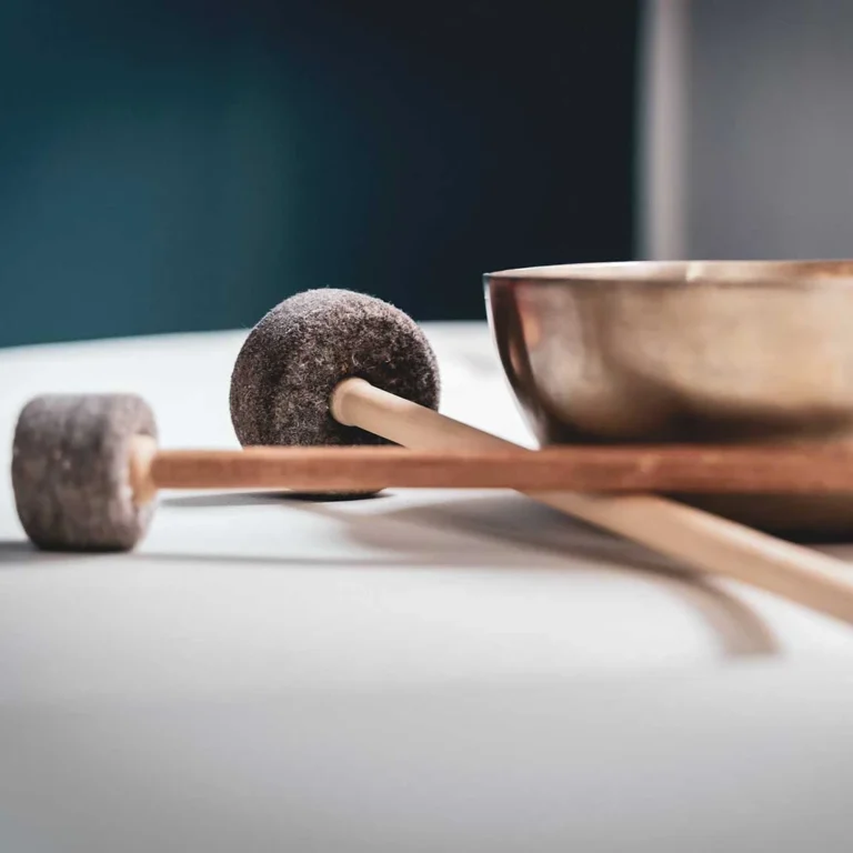 Klangschale mit zwei Klöppeln auf hellem Untergrund