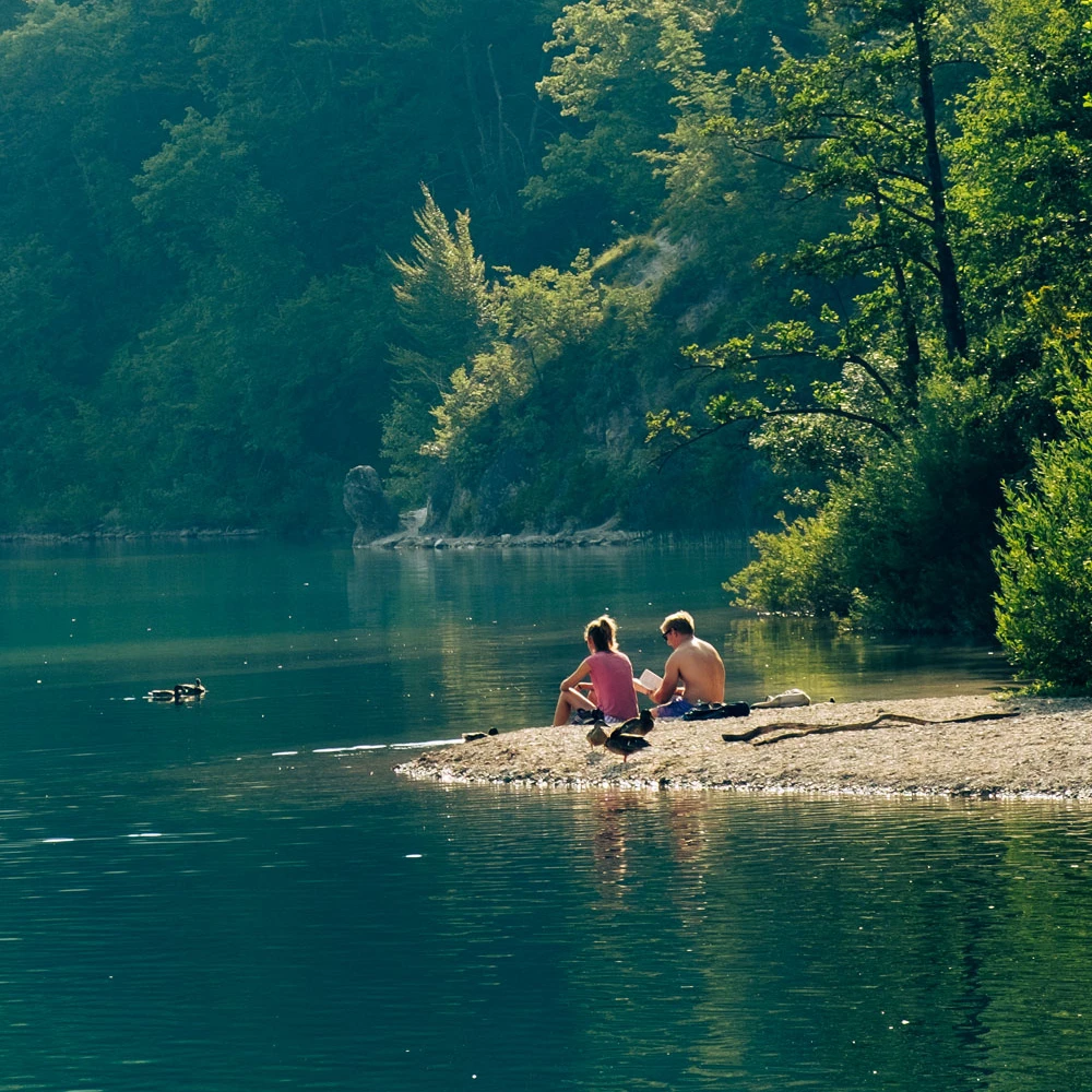 Ein Pärchen sitzt am Ufer eines ruhigen Sees