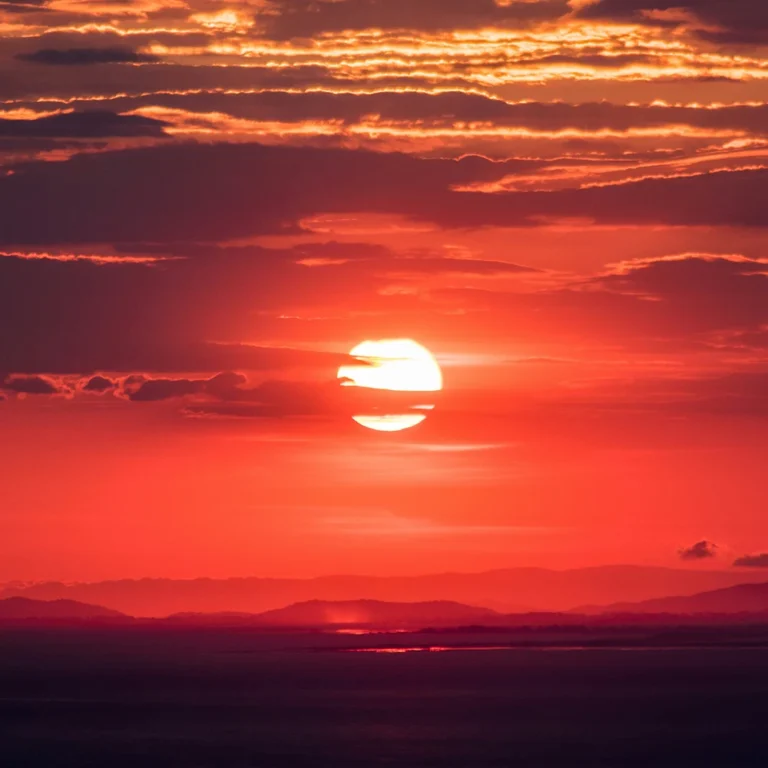 Sonnenuntergang, tiefroter Himmel mit Berglandschaft in der ferne