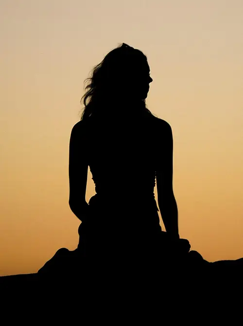 Silhouette einer sitzenden Frau nach einem Sonnenuntergang