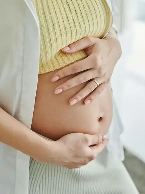 Schwangere Frau hält schützend den Bauch