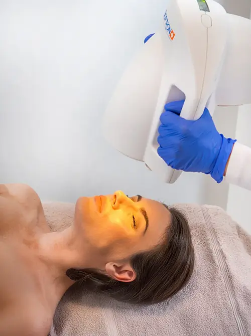 Gesichtsbehandlung mit einer Bioptron-Lampe bei liegender Frau